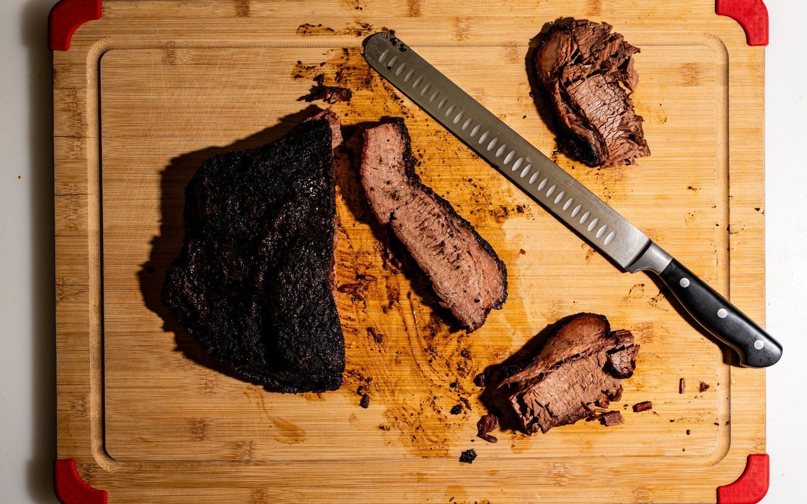 A whole brisket on butcher paper with a boning knife on a steel counter