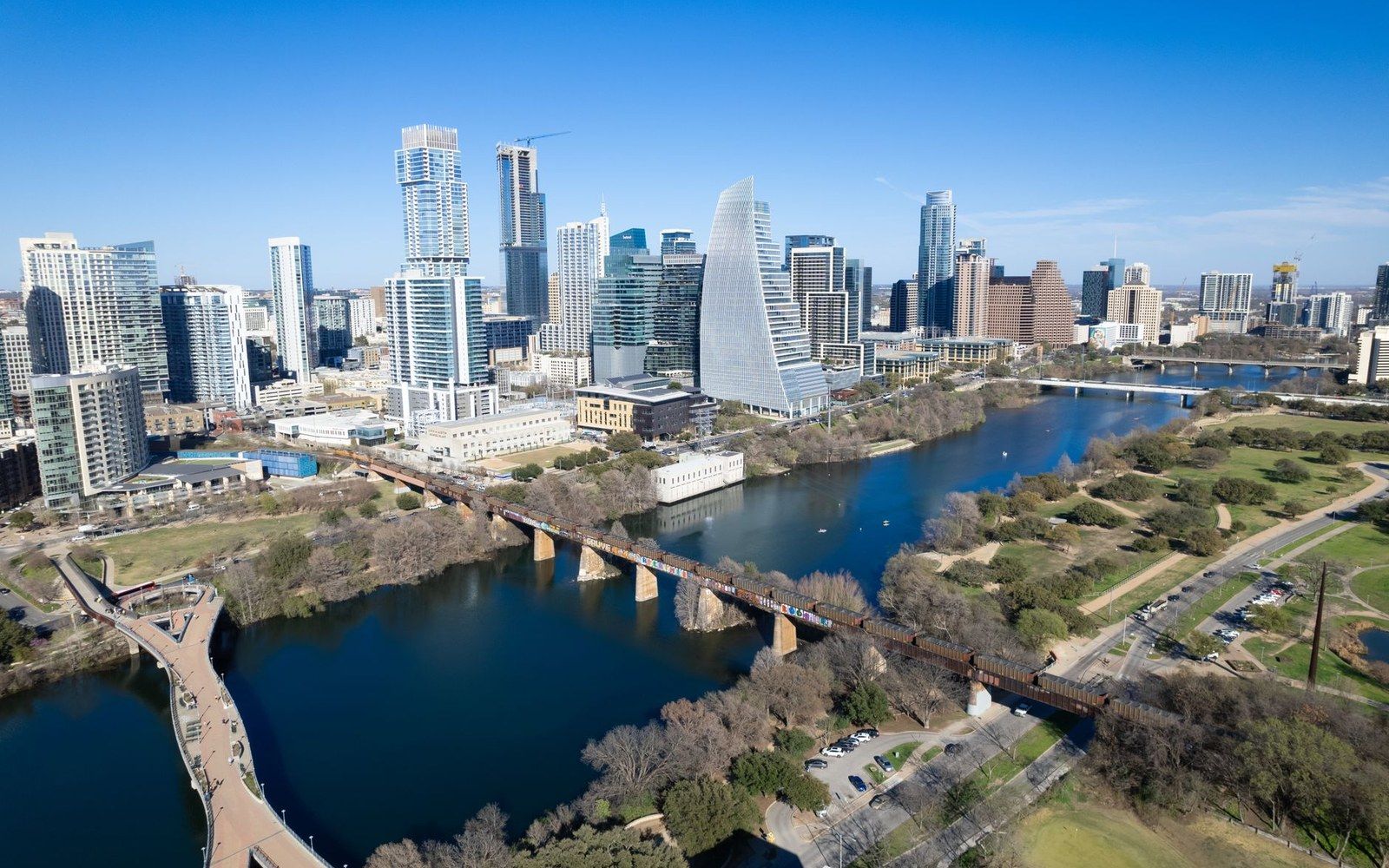 Aerial view of downtown Austin's skyline along the river with bridges and parkland