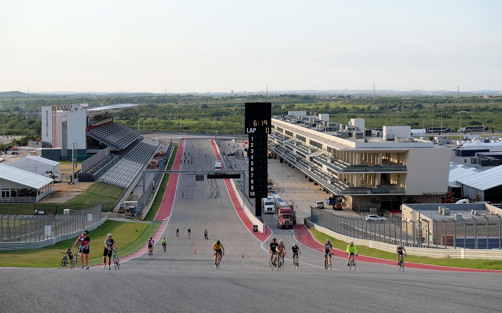 Cyclists ride up the main straight past the grandstand and pit building at Circuit of the Americas