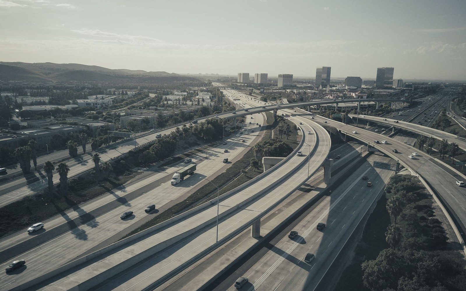 Aerial view of a sprawling highway interchange with light traffic near a distant skyline
