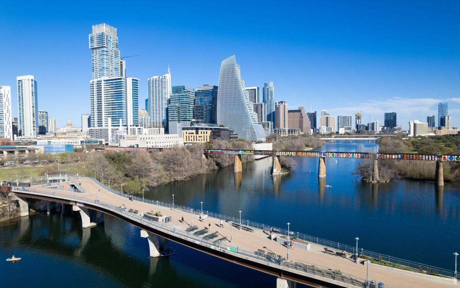 Downtown Austin skyline rises beyond a pedestrian bridge over the Colorado River