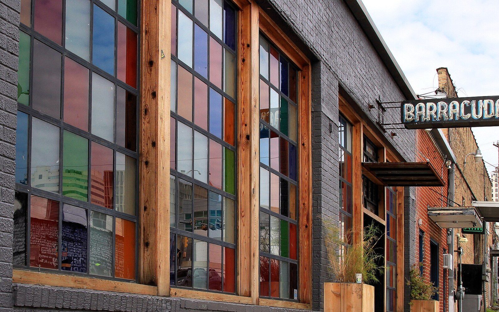 Colorful stained-glass windows line a brick building's facade beside a Barracuda sign