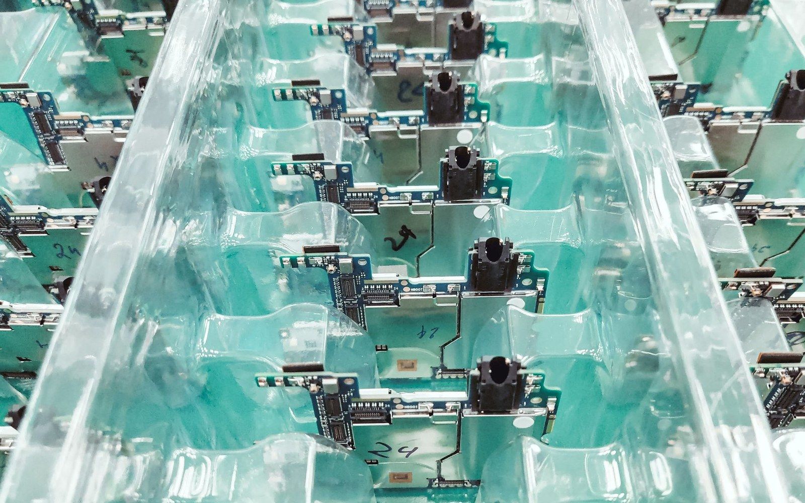 Rows of circuit boards with sensors embedded in clear plastic trays on a production line