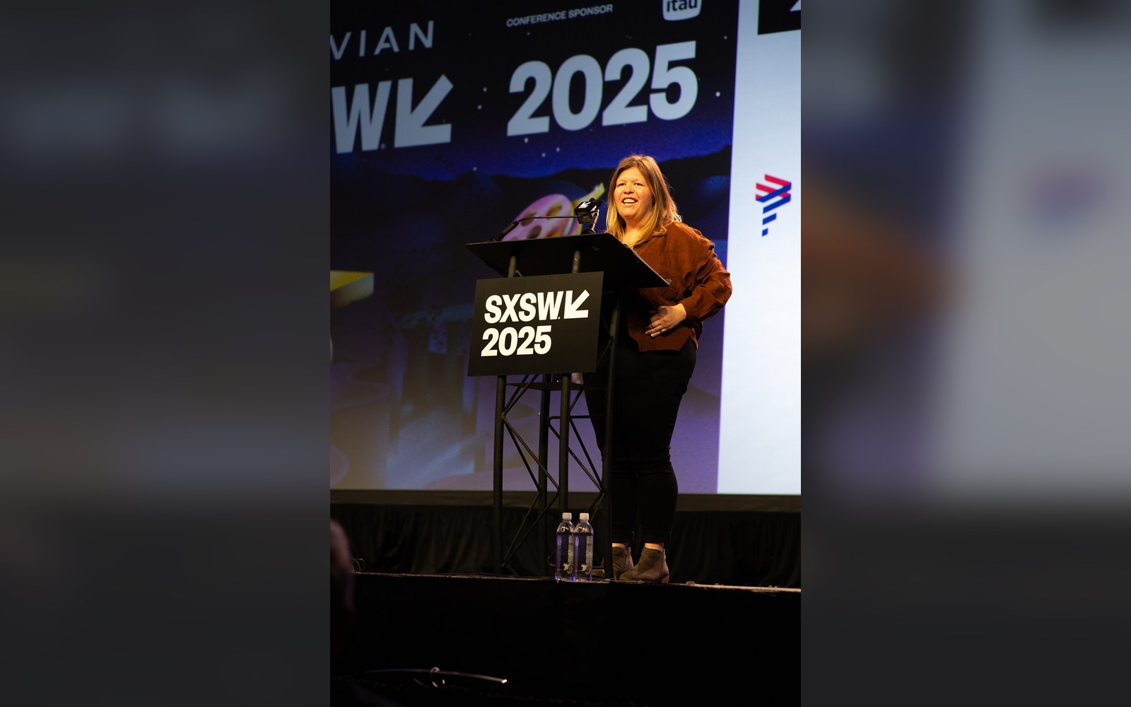 Woman laughing at a podium on stage bearing the SXSW 2025 logo