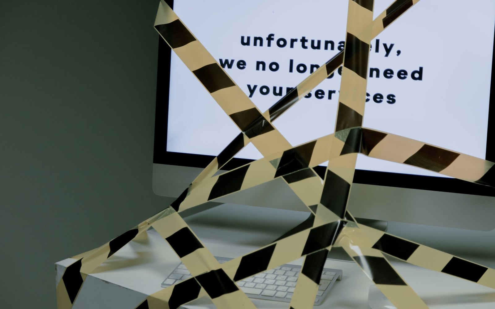 Hazard tape crisscrosses a computer monitor displaying a termination message on screen
